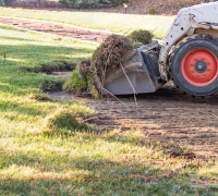 Professional landscaping equipment in action, clearing a yard for a new landscape design.